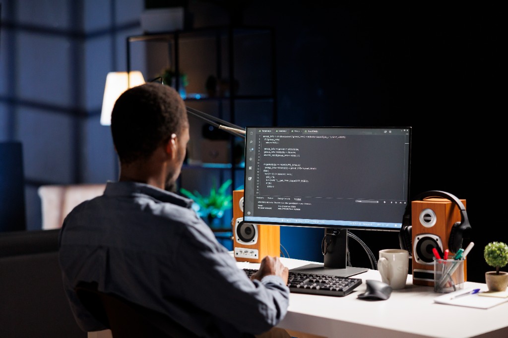 A person working at a desk with code on the screen.